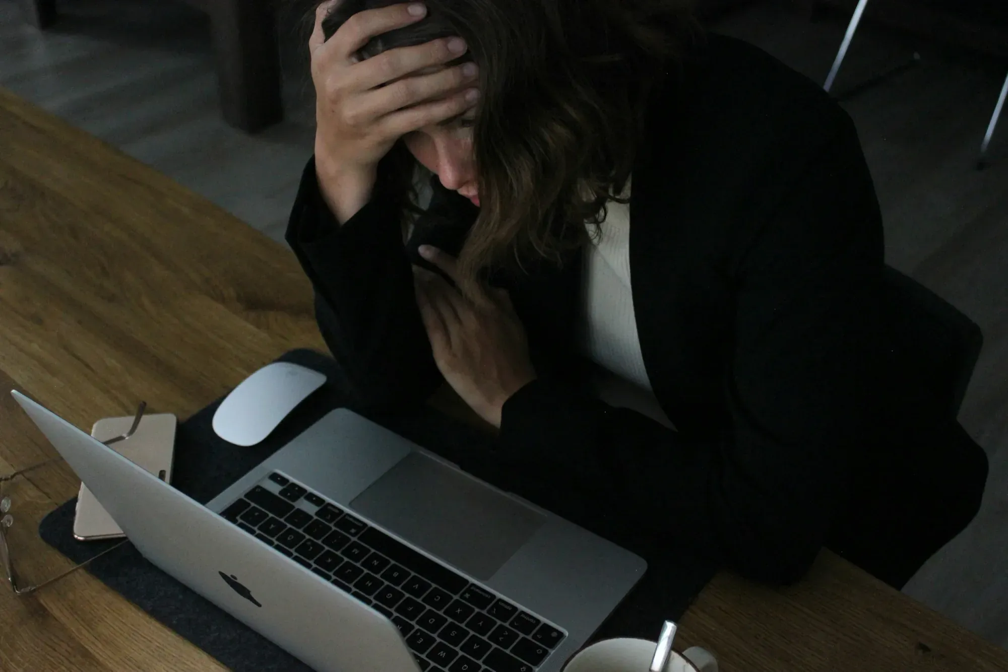 Frustrated woman looking into a computer screen with her hand on her head.